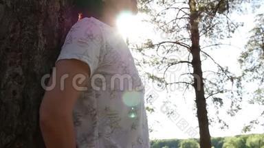一个年轻的游客站在森林里的一棵树上。 在树林里休息和散步，在新鲜的空气中。